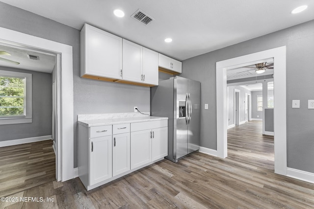 kitchen with white cabinetry, stainless steel refrigerator with ice dispenser, wood-type flooring, and a wealth of natural light