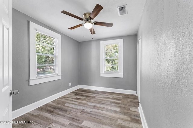 empty room featuring ceiling fan, light wood-type flooring, and a wealth of natural light