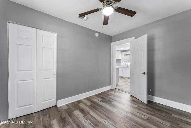 unfurnished bedroom featuring dark wood-type flooring, ceiling fan, and a closet