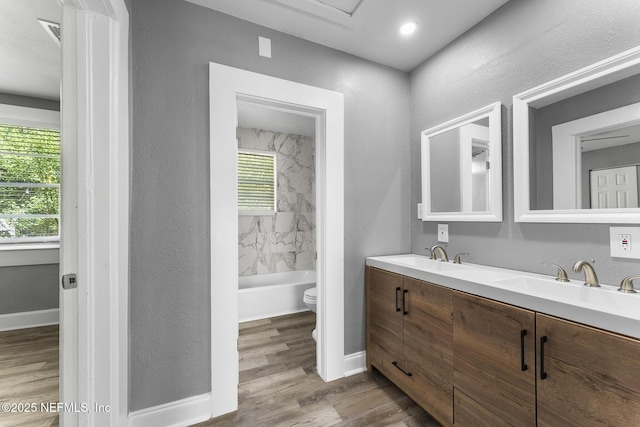 full bathroom with vanity, tiled shower / bath, wood-type flooring, and toilet