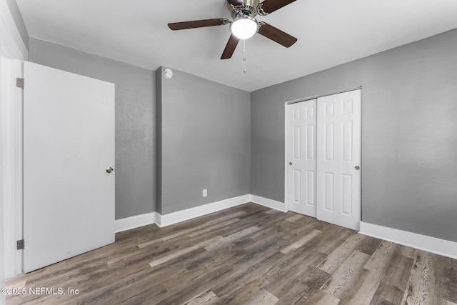 unfurnished bedroom with dark hardwood / wood-style floors, a closet, and ceiling fan