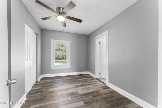 unfurnished bedroom featuring ceiling fan, dark hardwood / wood-style flooring, a closet, and a textured ceiling