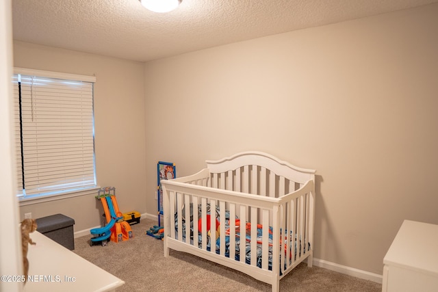 carpeted bedroom with a crib and a textured ceiling