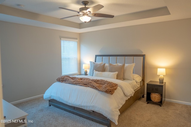 bedroom with light carpet, a tray ceiling, and ceiling fan