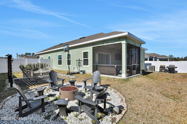 back of house featuring a sunroom, a yard, central AC unit, and a fire pit