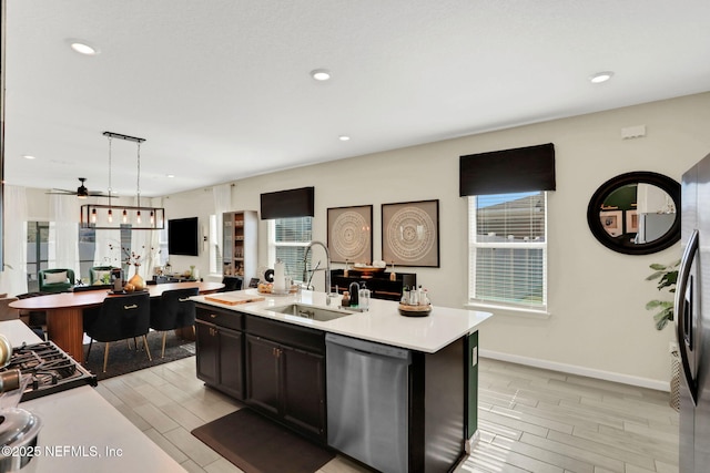 kitchen with sink, decorative light fixtures, stainless steel dishwasher, plenty of natural light, and an island with sink