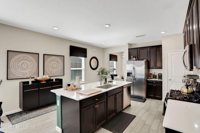 kitchen with tasteful backsplash, sink, a kitchen island with sink, stainless steel appliances, and dark brown cabinets