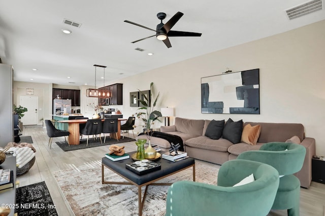 living room with ceiling fan and light hardwood / wood-style flooring