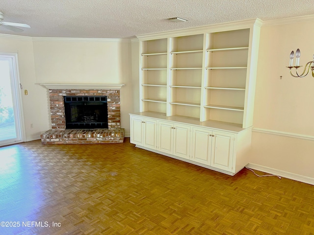 unfurnished living room featuring a fireplace, ornamental molding, light parquet flooring, and a textured ceiling