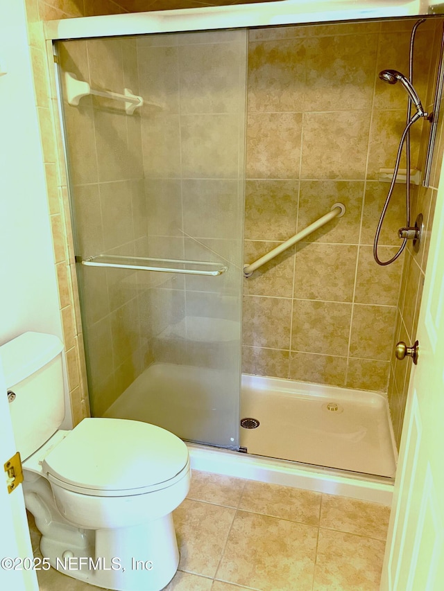 bathroom featuring tile patterned floors, toilet, and walk in shower