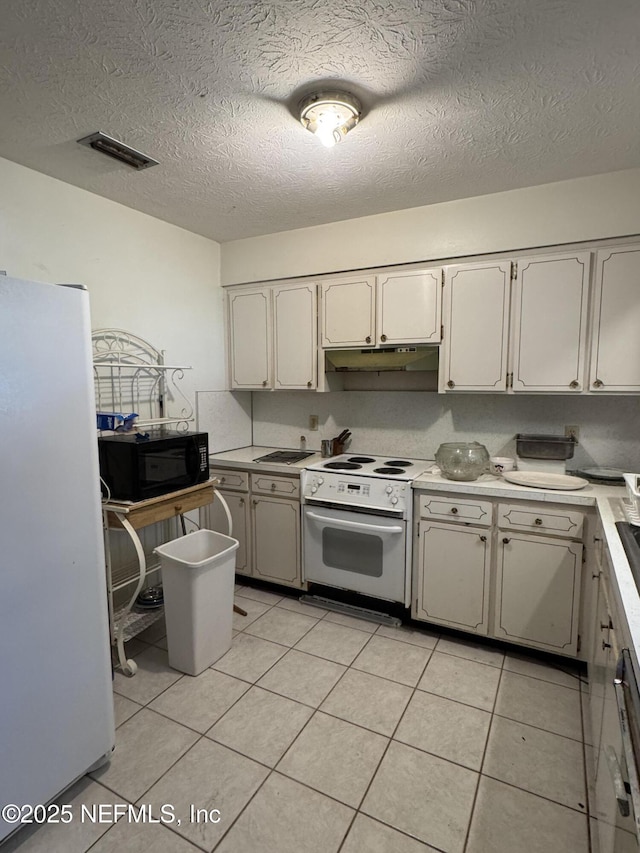 kitchen with fridge, white electric range oven, white cabinets, light tile patterned flooring, and a textured ceiling