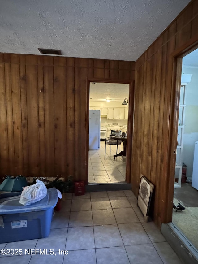 hall featuring light tile patterned flooring and wooden walls