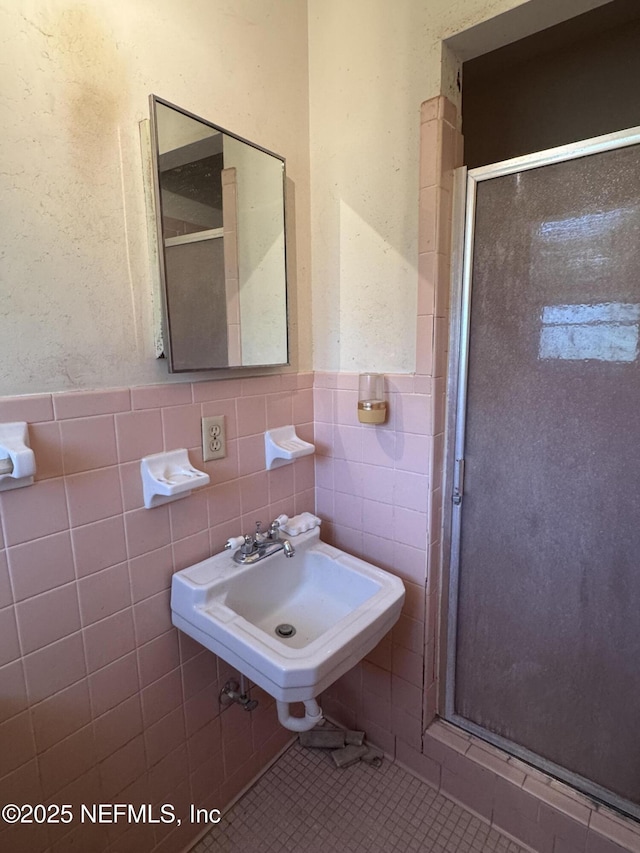 bathroom featuring an enclosed shower, sink, tile walls, and tile patterned floors