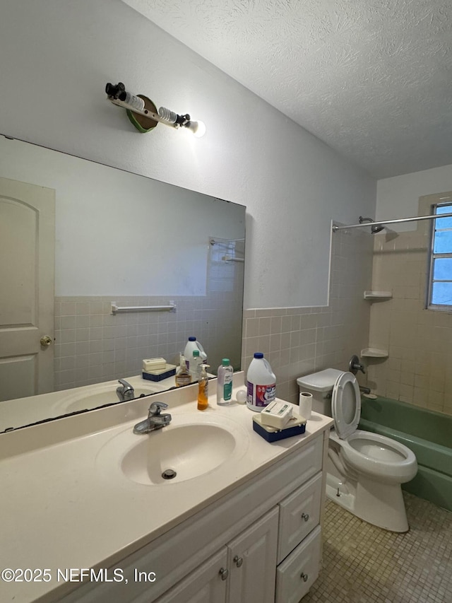 full bathroom with tile patterned floors, toilet, a textured ceiling, vanity, and tiled shower / bath combo