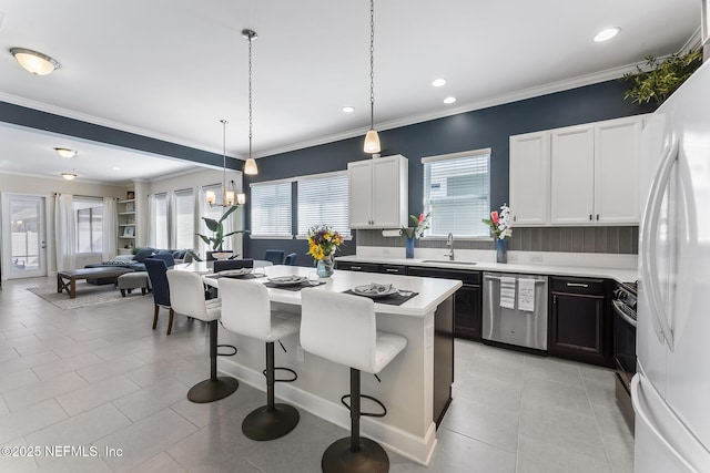 kitchen featuring a kitchen bar, white cabinetry, stainless steel dishwasher, a kitchen island, and white fridge