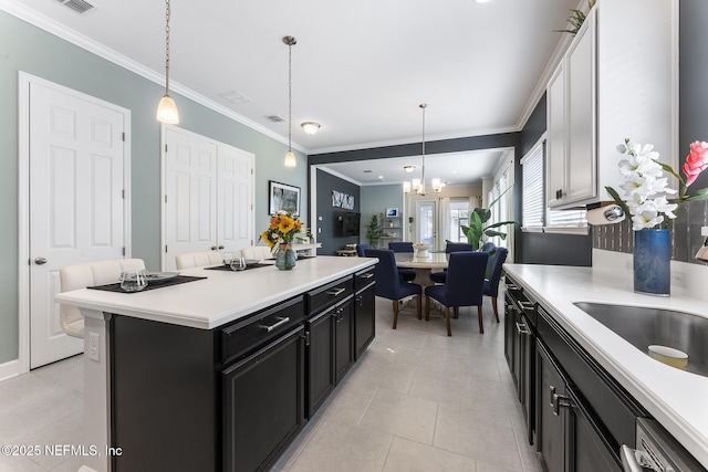 kitchen with pendant lighting, light tile patterned floors, crown molding, and a kitchen island