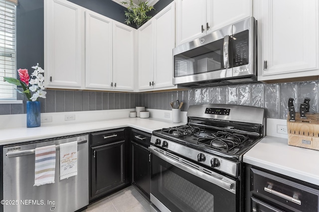 kitchen featuring tasteful backsplash, white cabinetry, appliances with stainless steel finishes, and light tile patterned flooring