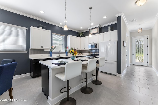 kitchen with sink, a kitchen island, hanging light fixtures, and appliances with stainless steel finishes