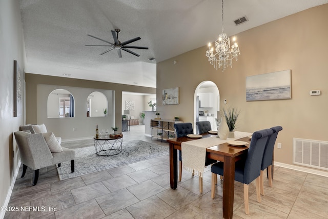 dining space featuring a towering ceiling, ceiling fan with notable chandelier, and a textured ceiling