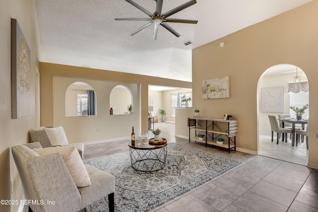 tiled living room featuring lofted ceiling, ceiling fan, and a textured ceiling