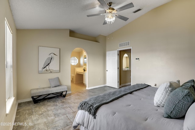 bedroom with ceiling fan, vaulted ceiling, a textured ceiling, and ensuite bathroom