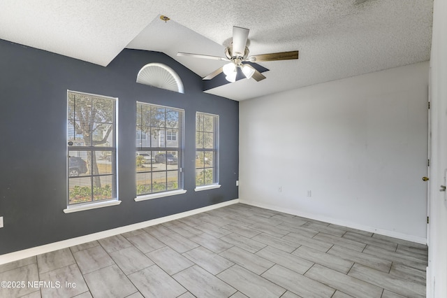 spare room featuring lofted ceiling, a healthy amount of sunlight, a textured ceiling, and ceiling fan