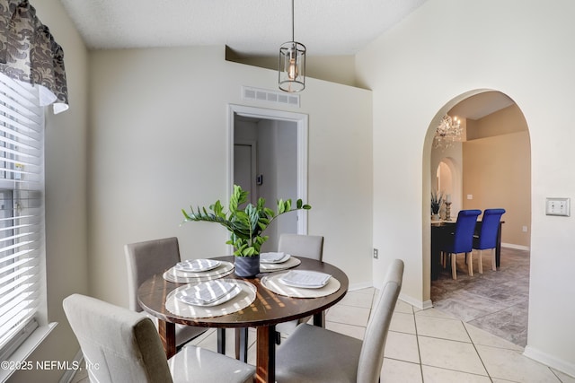 dining area featuring light tile patterned floors, vaulted ceiling, and a textured ceiling