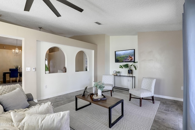 living room with vaulted ceiling, ceiling fan with notable chandelier, and a textured ceiling