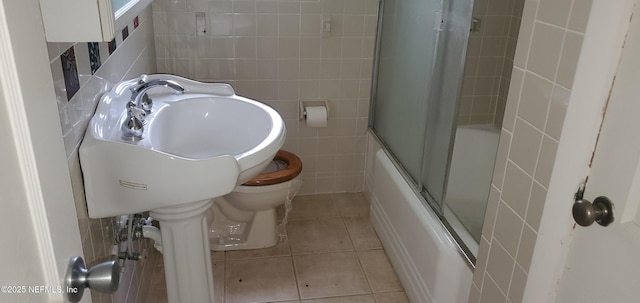 full bathroom featuring sink, enclosed tub / shower combo, tile patterned flooring, tile walls, and toilet