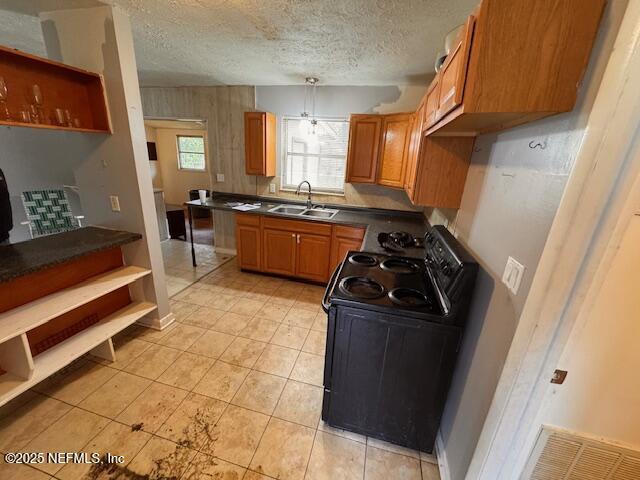 kitchen with light tile patterned floors, black electric range oven, sink, hanging light fixtures, and a textured ceiling