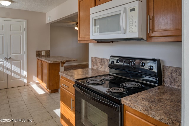 kitchen with a textured ceiling, light tile patterned floors, electric range, and ceiling fan