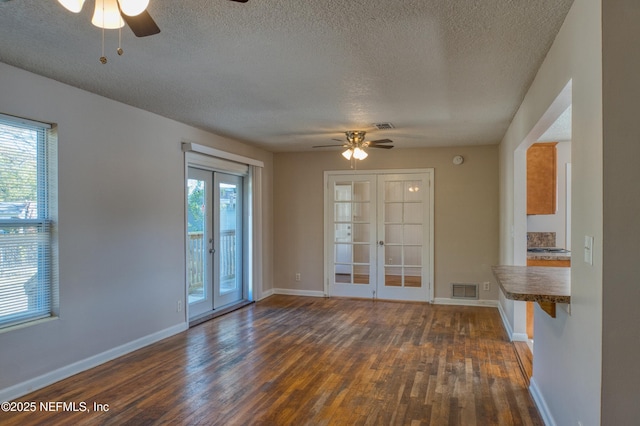 unfurnished room with a healthy amount of sunlight, dark hardwood / wood-style floors, and french doors