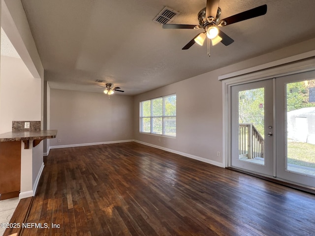 unfurnished living room with ceiling fan, plenty of natural light, dark hardwood / wood-style flooring, and french doors