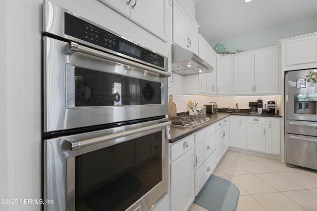 kitchen featuring white cabinetry, backsplash, light tile patterned flooring, and appliances with stainless steel finishes