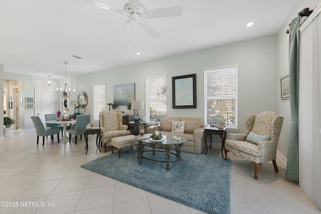 tiled living room with ceiling fan with notable chandelier