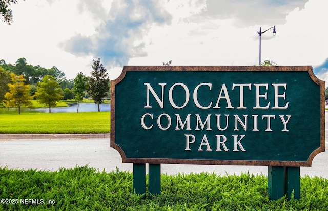 community sign featuring a water view and a lawn