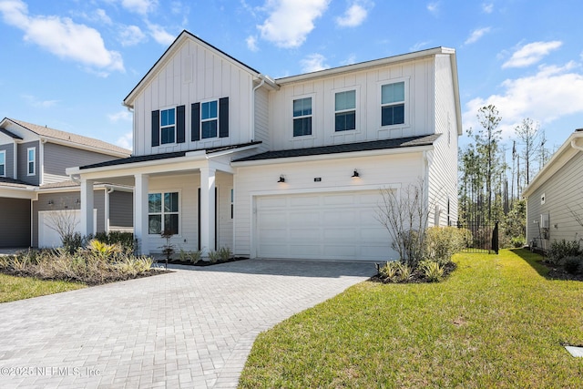 modern farmhouse style home featuring an attached garage, fence, decorative driveway, a front lawn, and board and batten siding