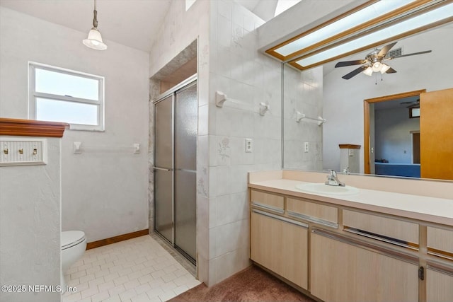 bathroom with tile patterned floors, toilet, a shower with shower door, vanity, and ceiling fan