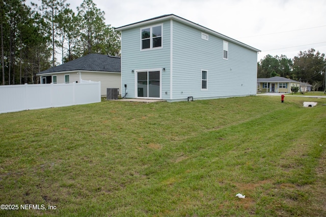 rear view of property with central AC and a yard