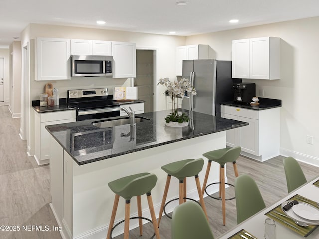 kitchen featuring stainless steel appliances, sink, dark stone counters, and white cabinets