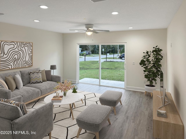 living room featuring a healthy amount of sunlight, ceiling fan, light hardwood / wood-style flooring, and a textured ceiling