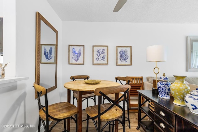 dining room featuring a textured ceiling, wood-type flooring, and ceiling fan