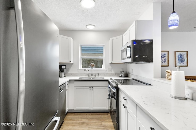 kitchen with appliances with stainless steel finishes, decorative light fixtures, sink, and white cabinets