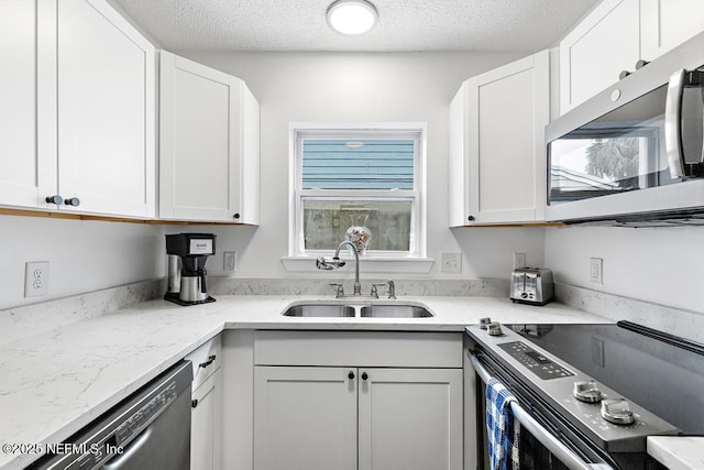 kitchen with stainless steel appliances, sink, white cabinets, and a textured ceiling