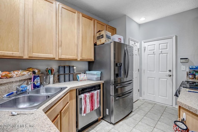 kitchen featuring light tile patterned flooring, appliances with stainless steel finishes, sink, light brown cabinets, and a textured ceiling