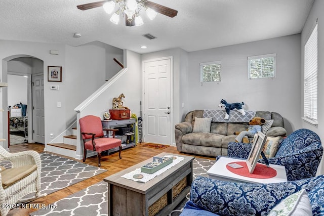 living room with hardwood / wood-style floors, a textured ceiling, and ceiling fan