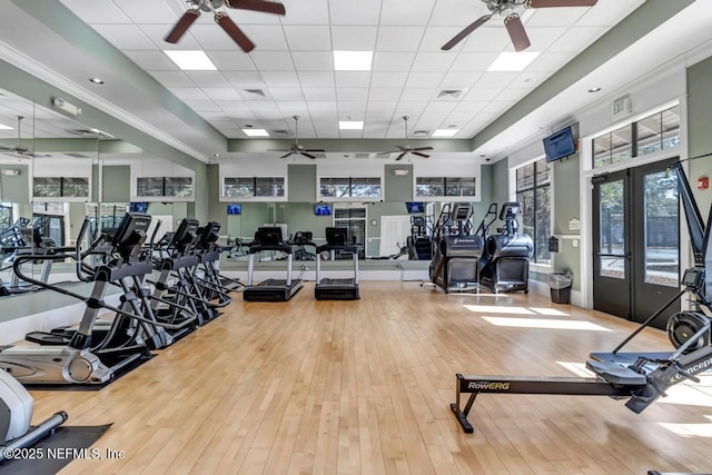 gym with french doors, ceiling fan, light hardwood / wood-style flooring, and a drop ceiling