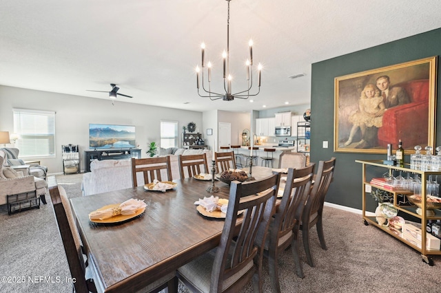 dining area with ceiling fan with notable chandelier and carpet