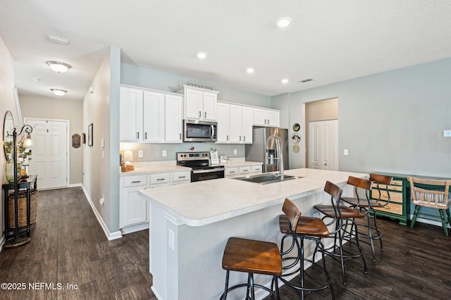 kitchen featuring sink, white cabinets, a kitchen bar, a kitchen island with sink, and stainless steel appliances