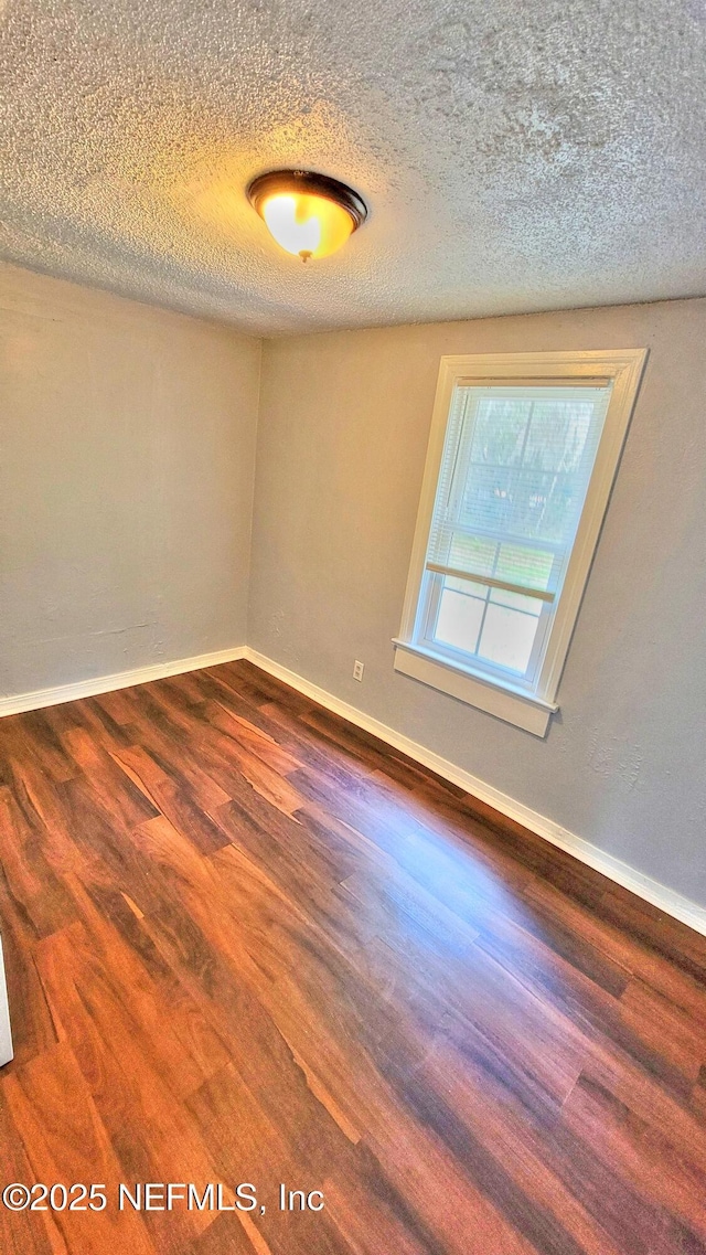 empty room featuring dark hardwood / wood-style flooring and a textured ceiling